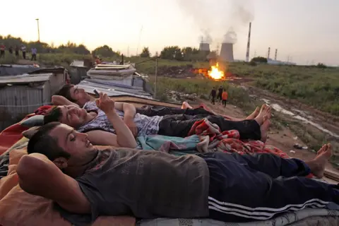 Reuters Migrants workers from Tajikistan relax on the roof of their shelter after working at local market outside Moscow, July 18 2011