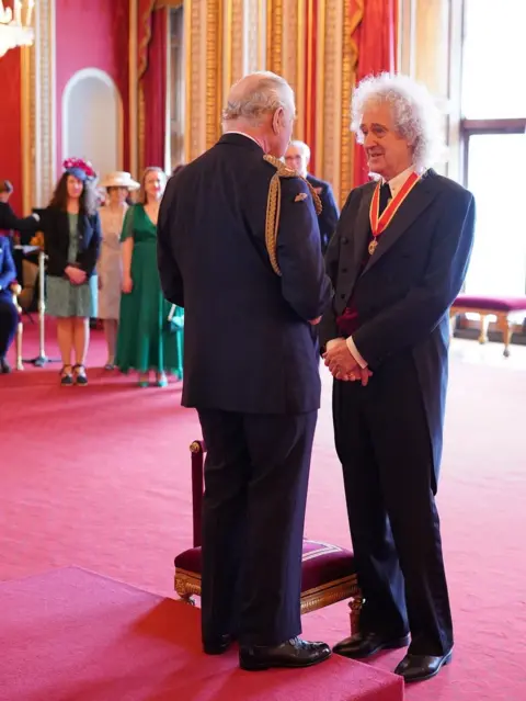 PA Media King Charles chats with Brian May after knighting him at Buckingham Palace