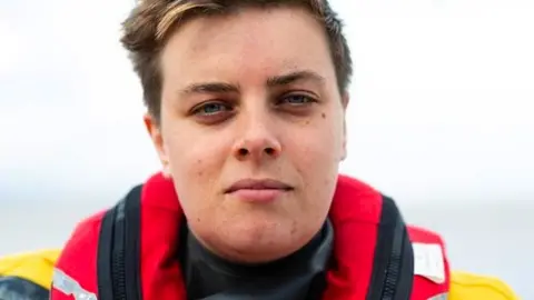 RNLI/Nathan Wiliams Susan Beaton looking directly at the camera. She is a woman with short brown hair and is dressed in her high-vis RNLI kit.
