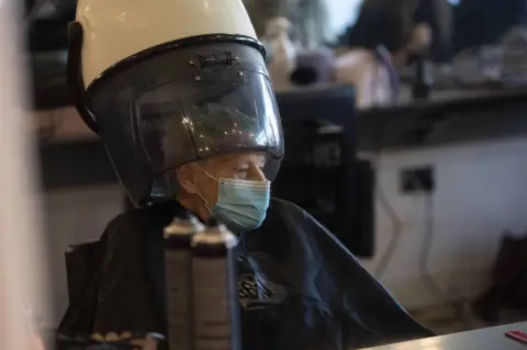 EPA An elderly woman wearing a mask in a hair salon