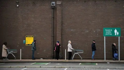Getty Images People waiting outside a Glasgow supermarket