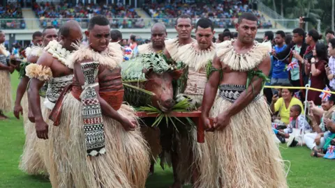 Reuters Men in traditional attire carry a roasted pig