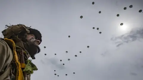 EPA Parachutist watches others drop to the ground