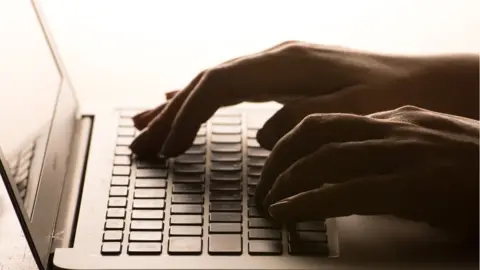 PA File photo of someone typing on a laptop keyboard