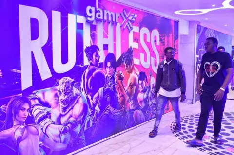 Pius Utomi Ekpei/AFP People walk past a huge billboard for a computer game.