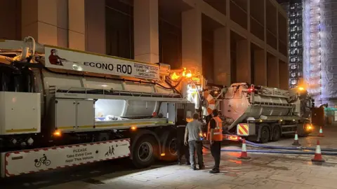 Cllr Rohit K Dasgupta Tankers with flashing lights parked outside the building at night