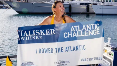 Atlantic Campaigns Atlantic rower Lara Vafiadis holds up a banner