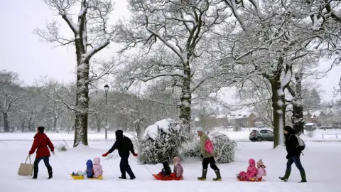 Getty Images Adults pulling children on sledges