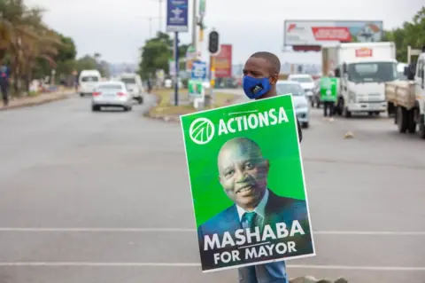 Getty Images An ActionSA campaigner holds a banner that reads "Mashaba for mayor" in Soweto, South Africa, on 27 October.