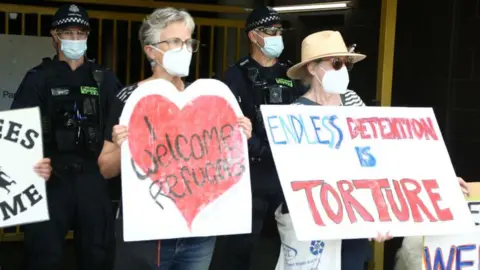 Getty Images Police stand in front of the Park Hotel car park entrance before Serbian tennis player Novak Djokovic arrives ahead of the Australian Open tennis tournament in Melbourne on January 14, 2022.