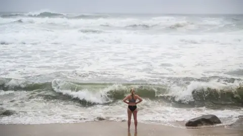 EPA A woman stands by rough sea in Bronte Beach, Sydney (10 Feb 2020)