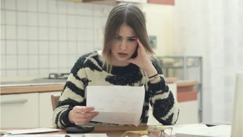 Getty Images a woman looks at a bill