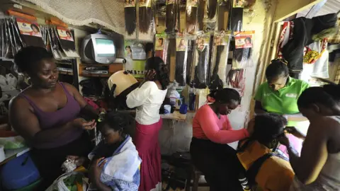 AFP Kenyan hairdressers attending to clients at a salon in the capital Nairobi - archive shot