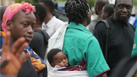 EPA A woman with her baby wrapped on her back.