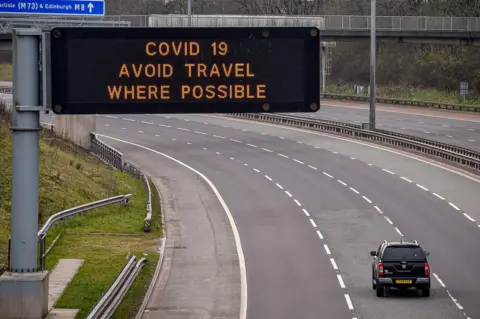 Getty Images A sign on the M8 motorway advises motorists to avoid travel where possible