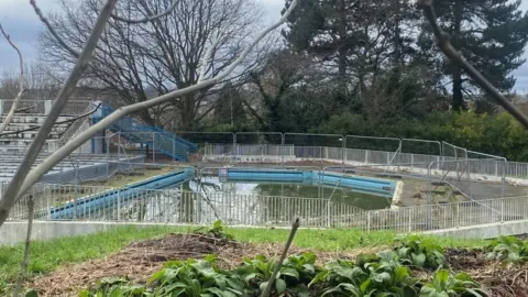 LUKE DEAL/ BBC Broomhill Lido, cordoned off by metal fencing, with green residual water at the base