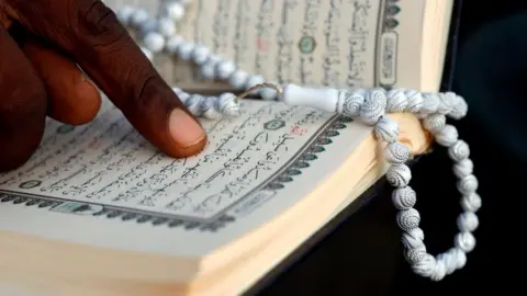 A man reading the Quran with prayer beads.
