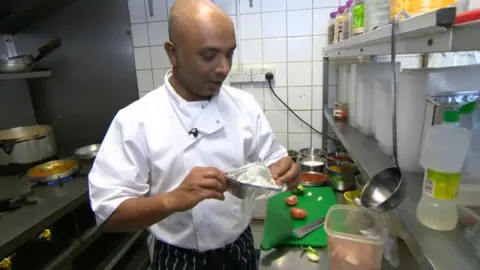 Moslek holding a metal takeaway tin