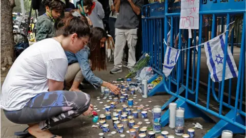 Getty Images Israelis light memorial candles at scene of attack in Tel Aviv (08/04/22)