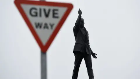 Reuters The statue of Edward Carson at Stormont next to a 'Give Way' road sign