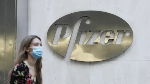 Getty Images Woman walks past Pfizer sign