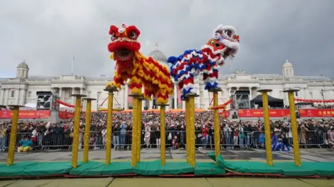 PA Media Chinese lion performance on raised poles.