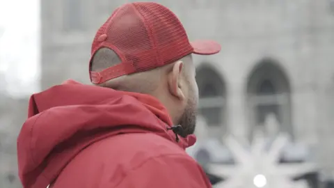 Eloise Alanna/BBC A photo of the back of Joshua's head in downtown Montreal. He is wearing a red baseball cap and parka.