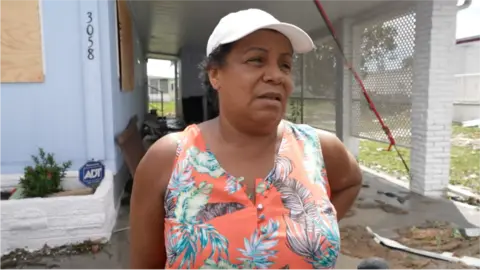 Diole Ado outside her damaged home in Fort Myers