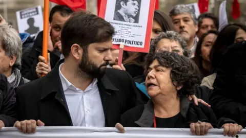 Getty Images El presidente chileno, Gabriel Boric, habla con la presidenta de la Asociación de Familiares de Detenidos y Desaparecidos de Chile, Alicia Lira, durante una marcha que conmemora el 50 aniversario del golpe militar liderado por el general Augusto Pinochet contra el presidente Salvador Allende, en Santiago, Chile. 10 de septiembre de 2023.