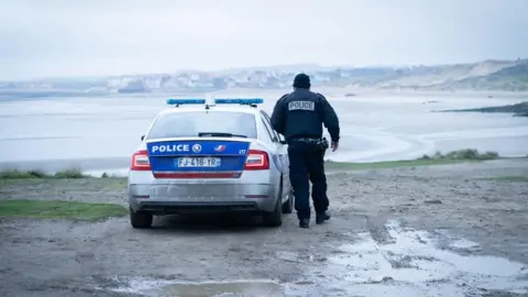 A photo from a PA media file of a French police officer overlooking a beach near Wimereux in France