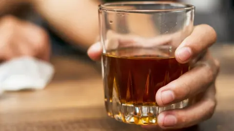 Getty Images A hand holding a glass of alcohol