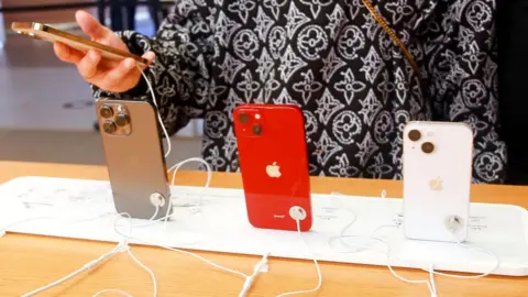 Getty Images Woman looks at Apple iPhones