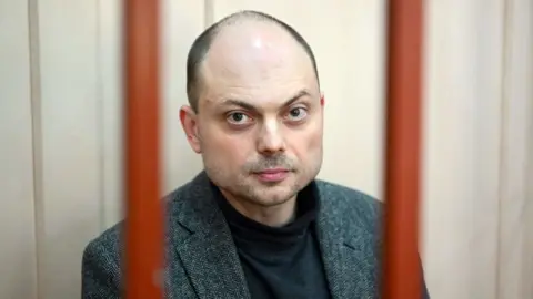 AFP Russian opposition activist Vladimir Kara-Murza sits on a bench inside a defendants' cage during a hearing at the Basmanny court in Moscow on October 10, 2022