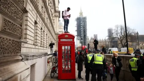 Reuters A protester standing on a telephone box in London