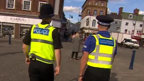 BBC Police officer walking alongside a PCSO