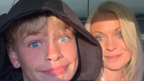 Family photo A boy pulls a face at the camera with his mother next to him, smiling