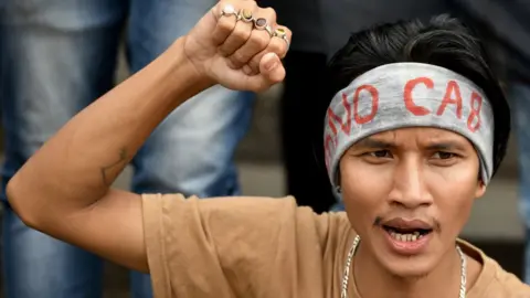 AFP A protester in Bangalore wearing a headband with "NO CAB" written on it