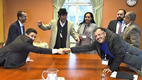 AFP Houthi delegate Abdelqader Mourtada (L) and government delegate Brigadier General Asker Zaeel shake hands at the negotiating table in Stockholm, 13 December