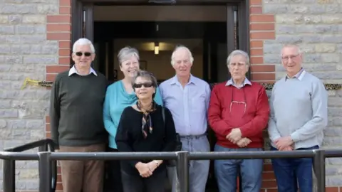 Six people stood in front of a library sign