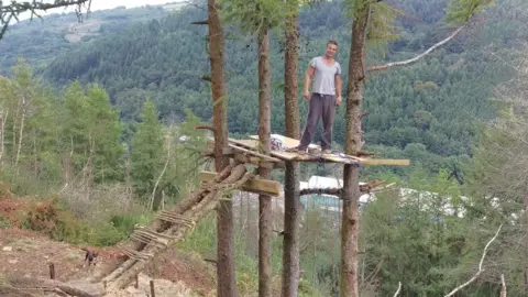 Wales News Service Mike Allen standing on a platform in the trees