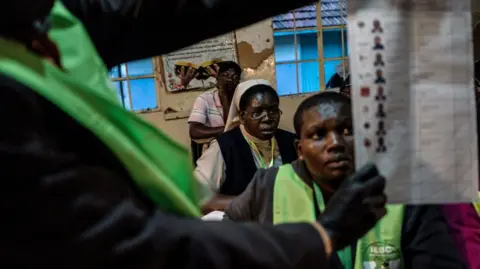 Election observers looks on as voting officials learn how to count ballots on August 8, 2017 at the Victoria primary school polling station in Kisumu