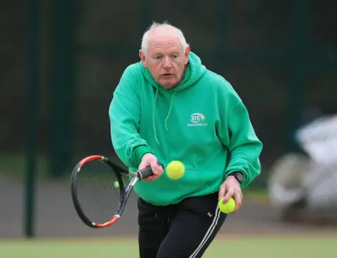 PA Media A tennis player hits a ball on a court