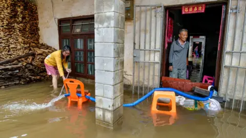 Getty Images Residents pump flood water out of their house