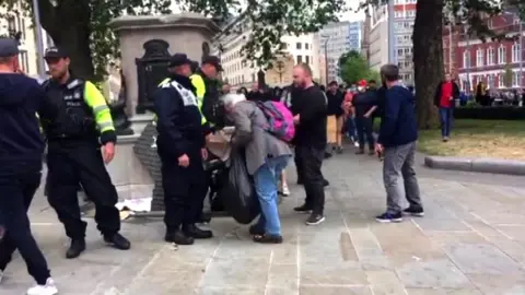 Elderly man putting Black Live Matters placards in a black bin bag