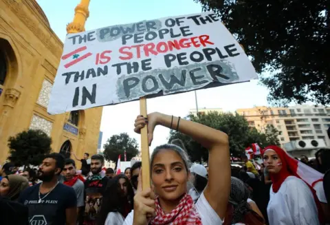 Getty Images A woman holds a sign while protesting in Beirut