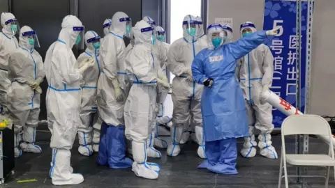 RAY YOUNG/ Feature China/Future Publishing via Get Image shows medical workers in Hazmat suits