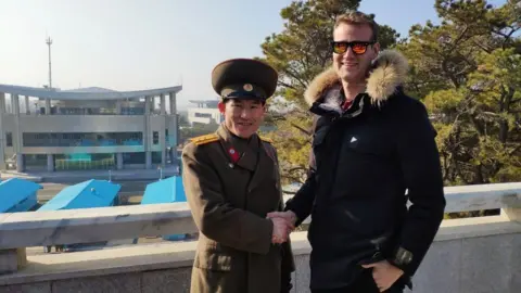 Young Pioneer Tours Rowan Beard shakes hands with a Republic of Korea (ROK) soldier