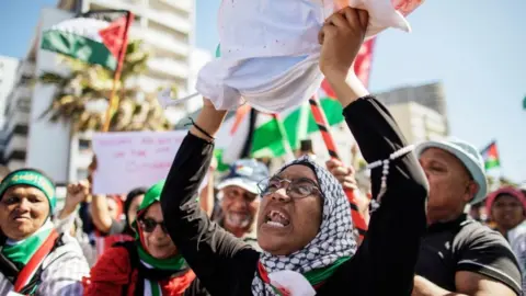 AFP A woman raises a mock body bag as pro-Palestinian supporters shout anti-Israeli slogans in Cape Town on November 12, 2023,