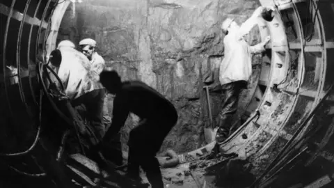 Historic England/John Laing Collection Men fit metalwork in tunnel