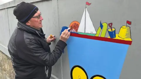 BBC Retired teacher Chris Cowie painting a mural to cover graffiti tags in Edinburgh